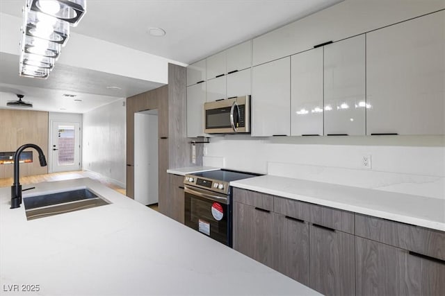kitchen with white cabinetry, modern cabinets, appliances with stainless steel finishes, and a sink