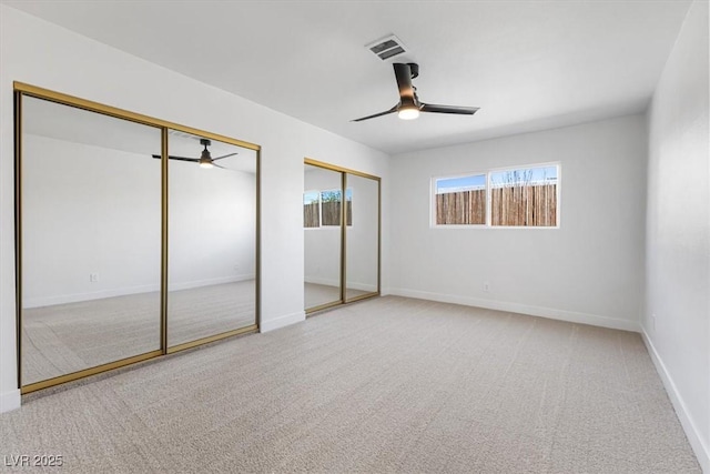 unfurnished bedroom featuring visible vents, two closets, a ceiling fan, carpet floors, and baseboards