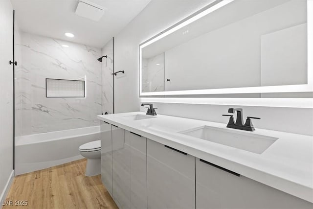 bathroom with shower / bath combination, toilet, wood finished floors, and a sink
