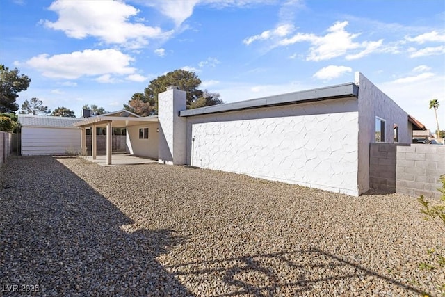 rear view of property featuring stucco siding, an outdoor structure, a fenced backyard, and a patio area