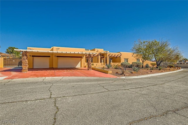 southwest-style home featuring a garage, stucco siding, driveway, and fence