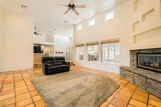 living area featuring tile patterned floors, visible vents, a wealth of natural light, and a ceiling fan