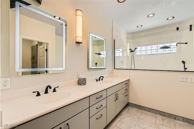 bathroom with double vanity, walk in shower, marble finish floor, and a sink