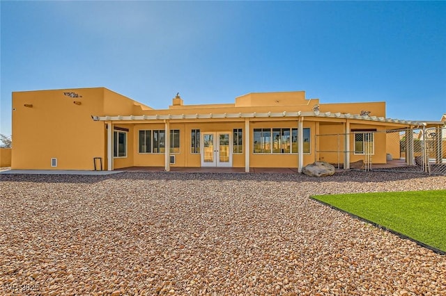 rear view of house with a patio, french doors, a chimney, and stucco siding