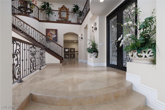 entrance foyer with stairs, a high ceiling, baseboards, and arched walkways