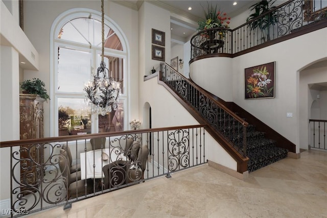 staircase featuring arched walkways, crown molding, an inviting chandelier, and a towering ceiling