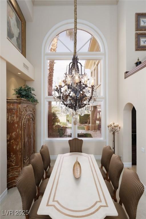 dining area featuring arched walkways, a towering ceiling, and a chandelier