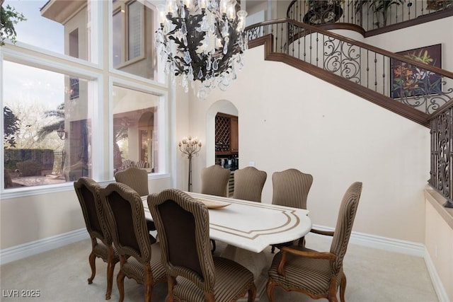 dining area featuring carpet flooring, baseboards, arched walkways, and a towering ceiling