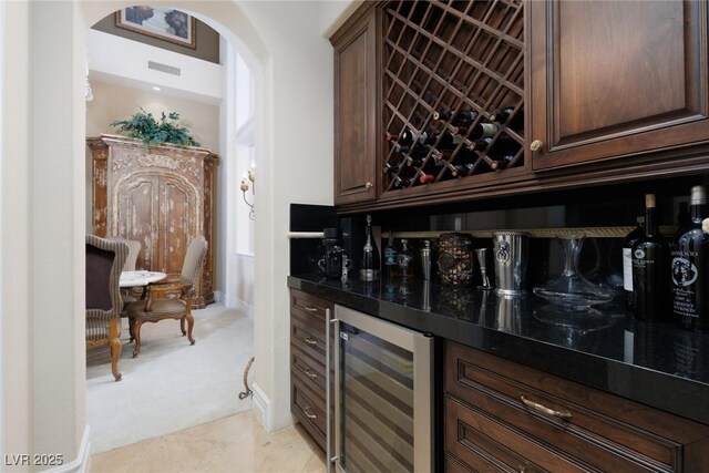 bar featuring visible vents, wine cooler, light tile patterned floors, arched walkways, and a bar