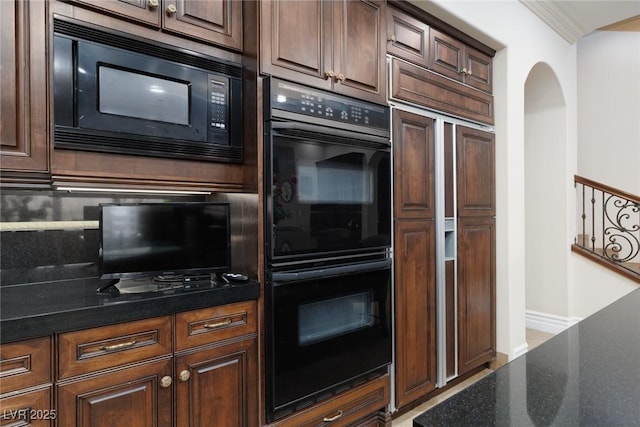 kitchen featuring dark brown cabinets, dark stone countertops, black appliances, and crown molding