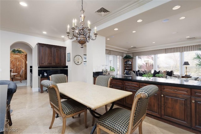 dining space featuring crown molding, a notable chandelier, arched walkways, and visible vents