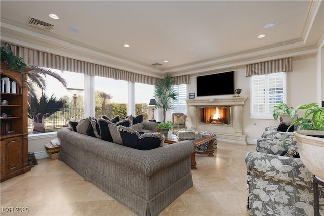 living room with crown molding, baseboards, visible vents, and a warm lit fireplace