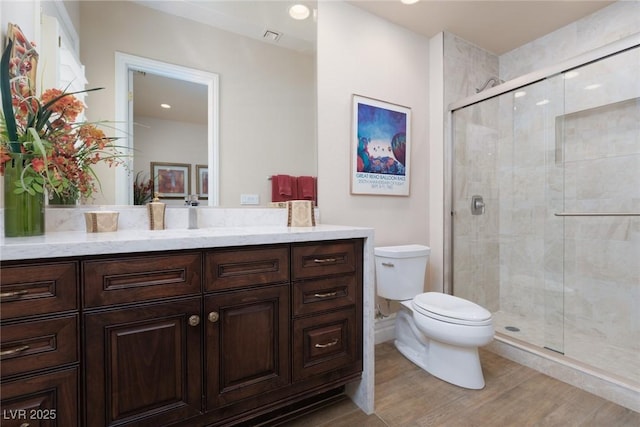 bathroom featuring vanity, wood finished floors, visible vents, a shower stall, and toilet