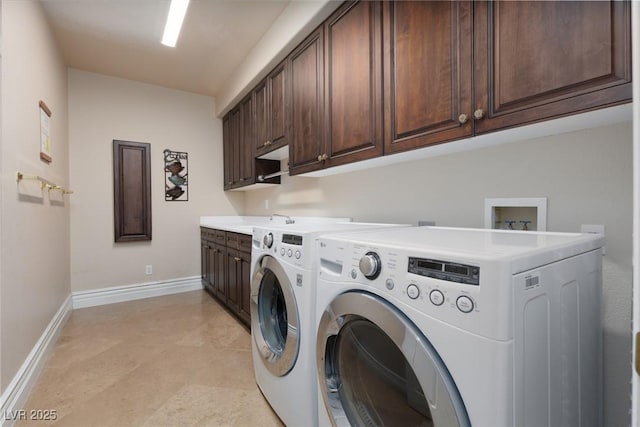 washroom with a sink, baseboards, cabinet space, and washing machine and clothes dryer