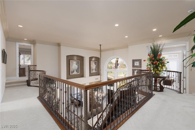 hall with an upstairs landing, recessed lighting, crown molding, and carpet