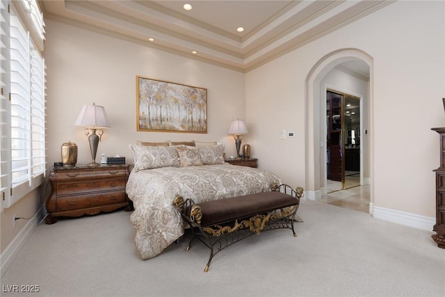 bedroom with a tray ceiling, arched walkways, carpet, and ornamental molding