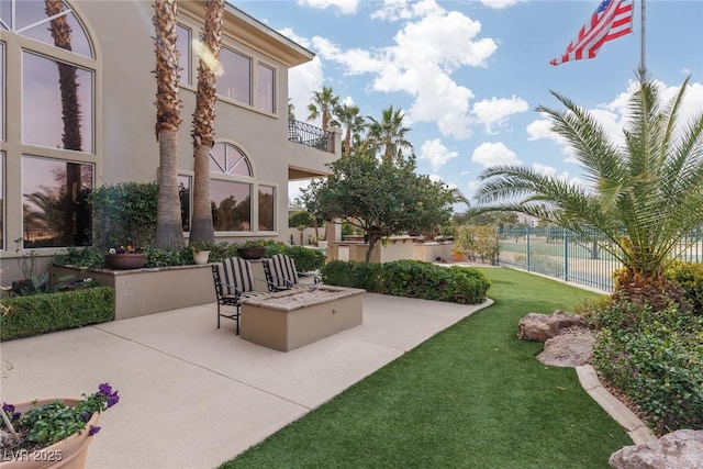 view of patio with a balcony, fence, and an outdoor fire pit