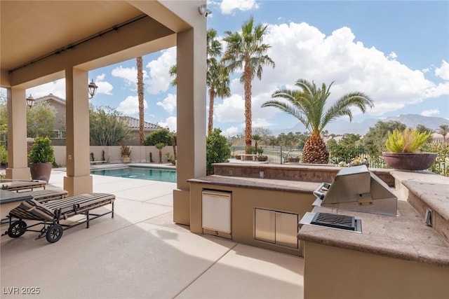 view of patio / terrace featuring a fenced in pool, an outdoor kitchen, and fence