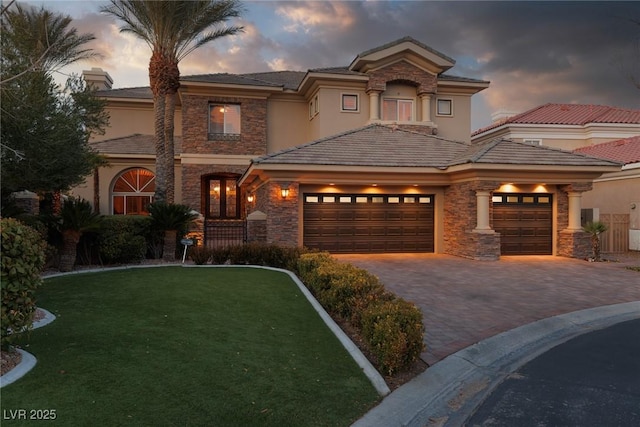 mediterranean / spanish home featuring a garage, stone siding, stucco siding, and decorative driveway