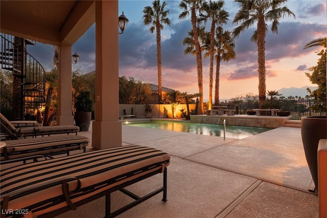 pool at dusk featuring a fenced backyard, stairway, a fenced in pool, and a patio