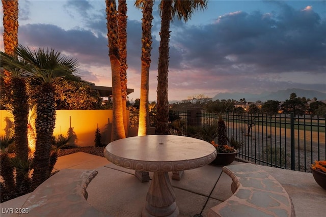 patio terrace at dusk featuring fence