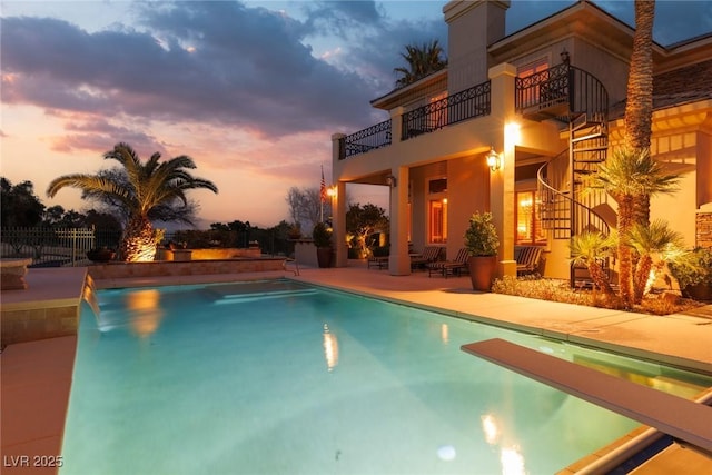 view of swimming pool featuring a patio area, a fenced in pool, fence, and a diving board