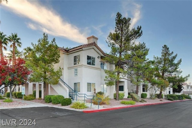 view of front of house with stairway, a chimney, and stucco siding