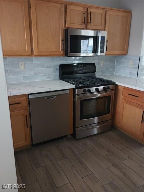 kitchen featuring stainless steel appliances, backsplash, and dark wood-style floors