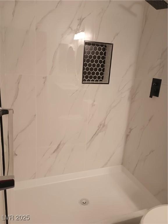 bathroom featuring a marble finish shower and toilet