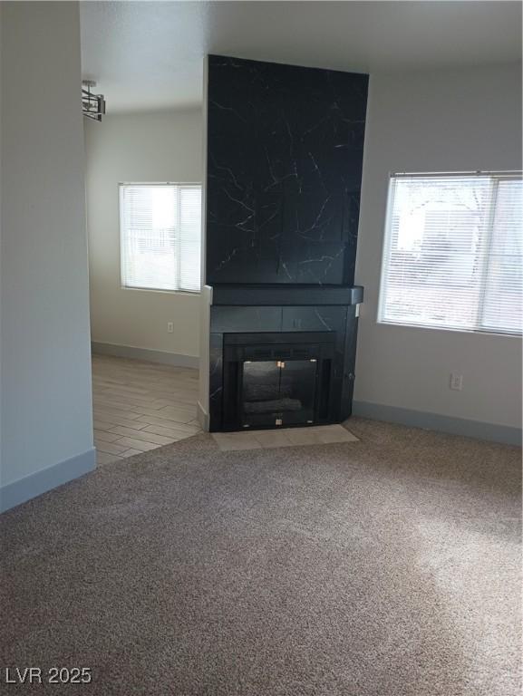 unfurnished living room with baseboards, a large fireplace, and carpet