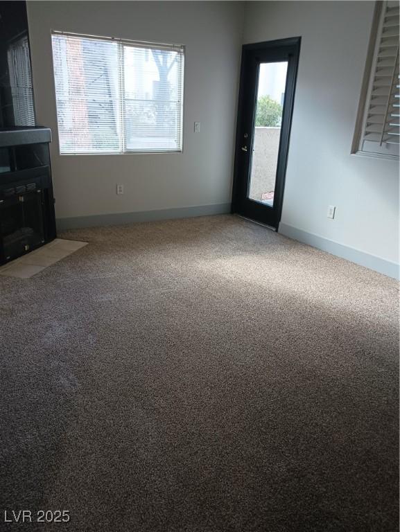 unfurnished living room featuring carpet and baseboards