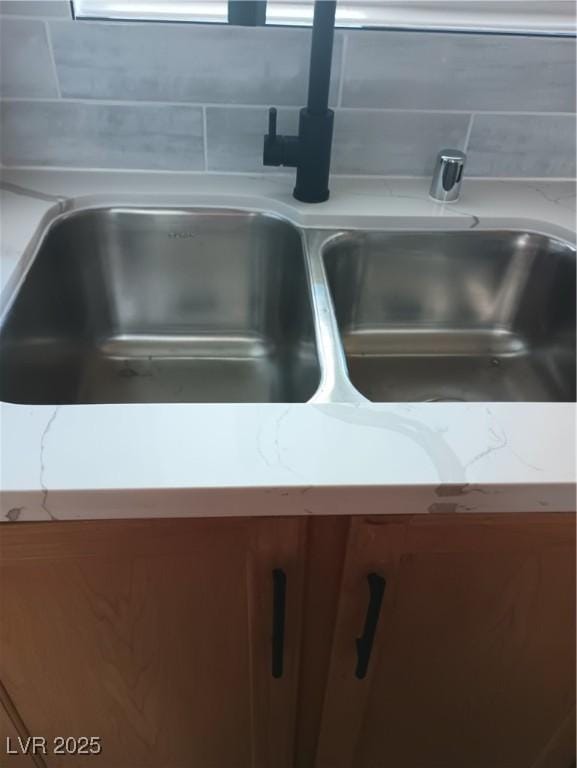 interior details with a sink, brown cabinets, and light stone countertops