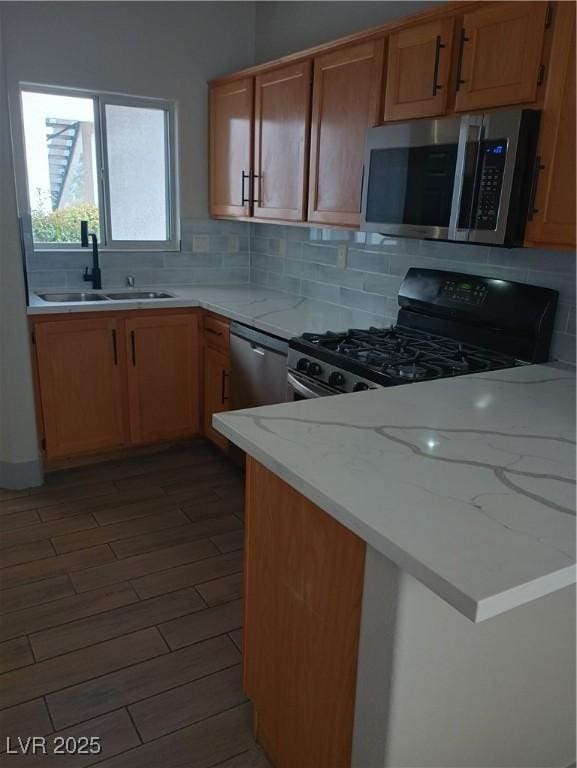 kitchen featuring a sink, tasteful backsplash, appliances with stainless steel finishes, and wood finished floors