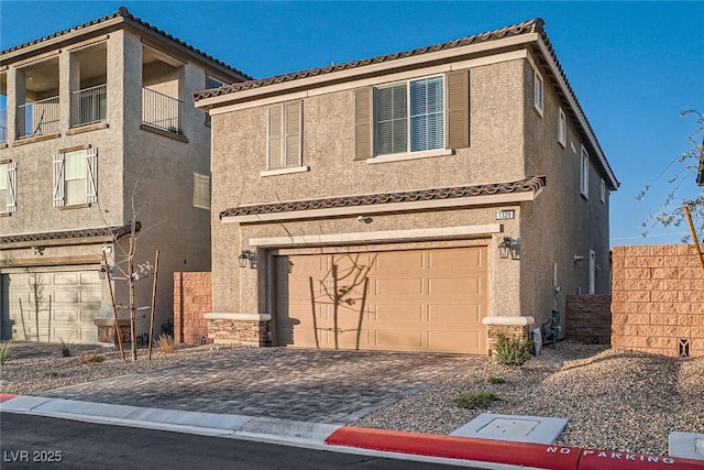 view of front of house with decorative driveway, a garage, and stucco siding