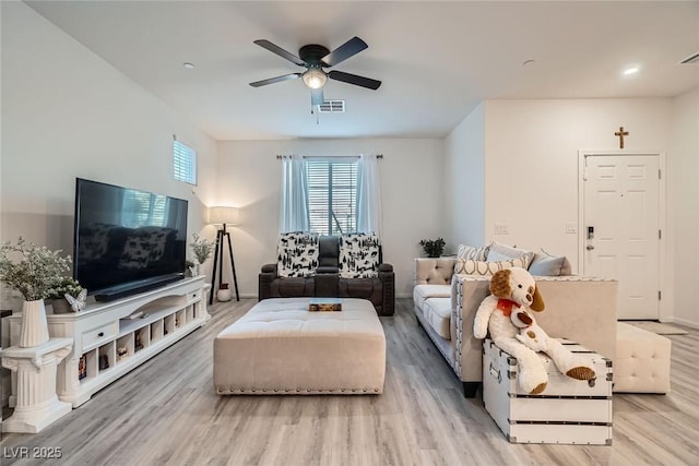 living room with baseboards, light wood-style floors, visible vents, and ceiling fan