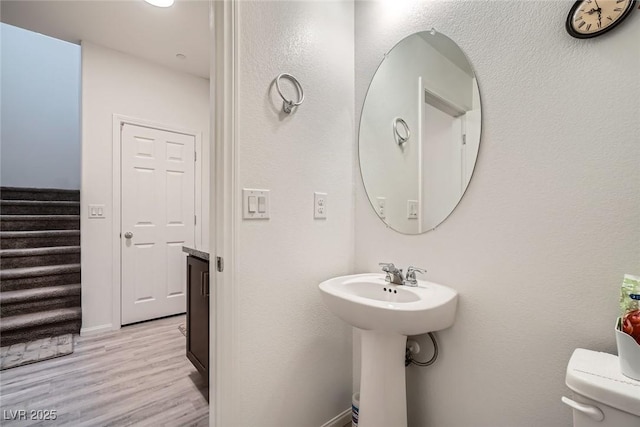 bathroom with toilet, wood finished floors, and baseboards