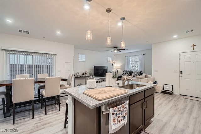 kitchen with stainless steel dishwasher, light wood-type flooring, visible vents, and a sink