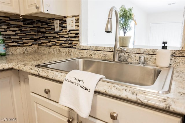 room details with light countertops, backsplash, and a sink