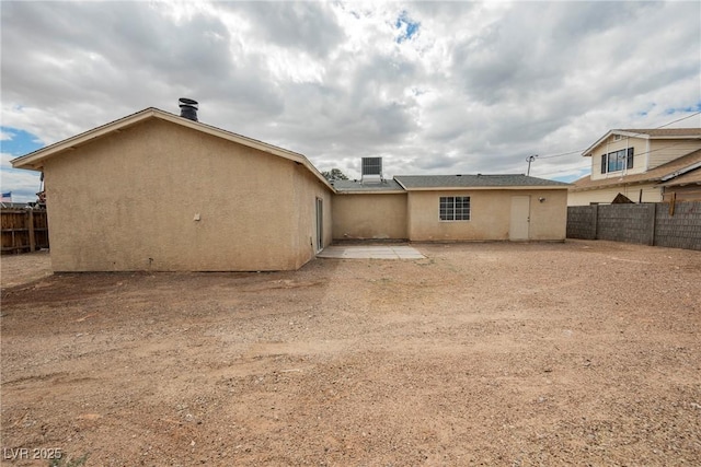 rear view of house featuring a fenced backyard and stucco siding