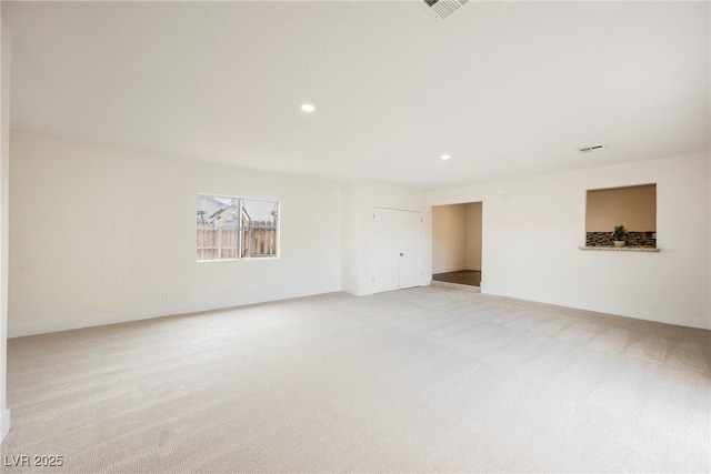 empty room with recessed lighting, light colored carpet, baseboards, and visible vents