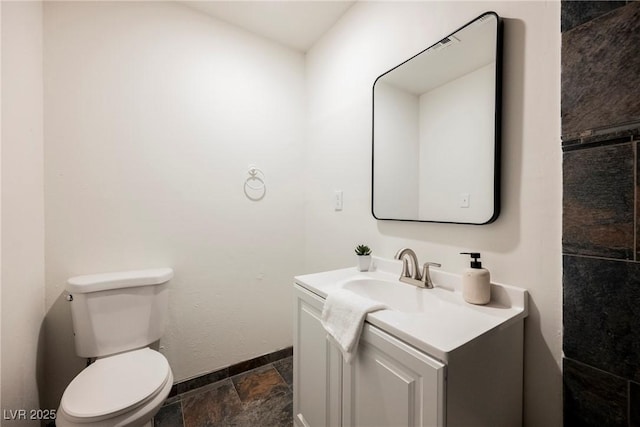 half bath with toilet, vanity, and baseboards