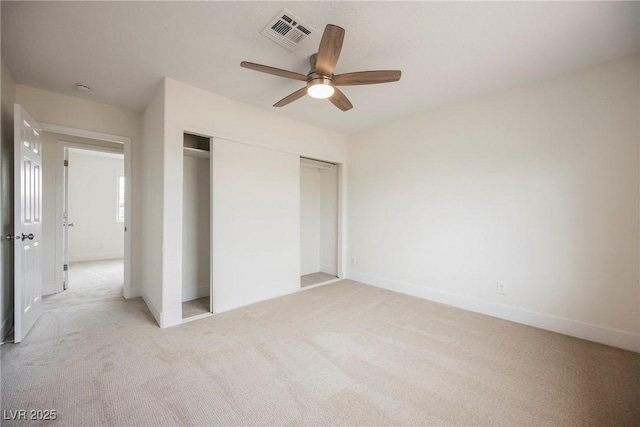 unfurnished bedroom featuring visible vents, a closet, baseboards, light colored carpet, and ceiling fan