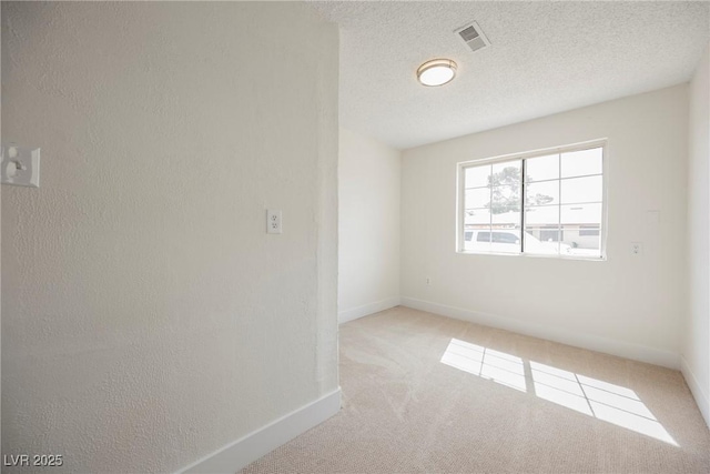 carpeted spare room featuring visible vents, a textured ceiling, baseboards, and a textured wall