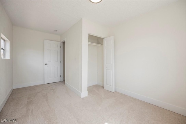 unfurnished bedroom with light colored carpet, baseboards, and a closet