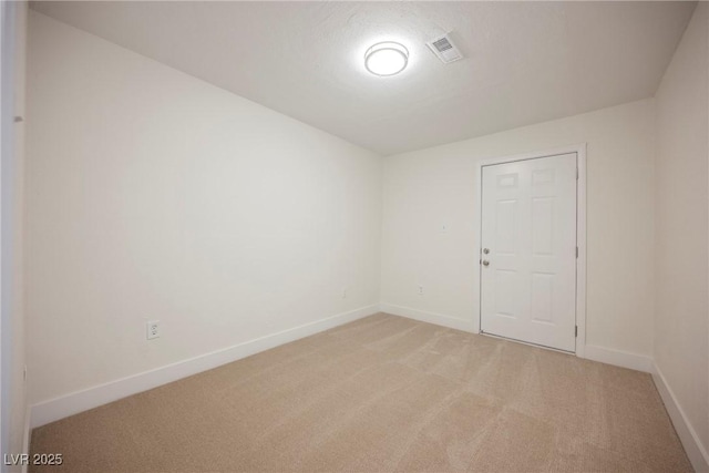 spare room featuring visible vents, baseboards, and light carpet