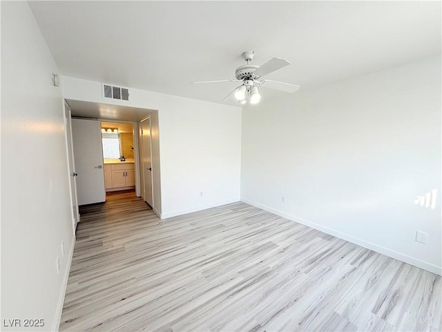 spare room featuring ceiling fan, visible vents, baseboards, and light wood-style flooring