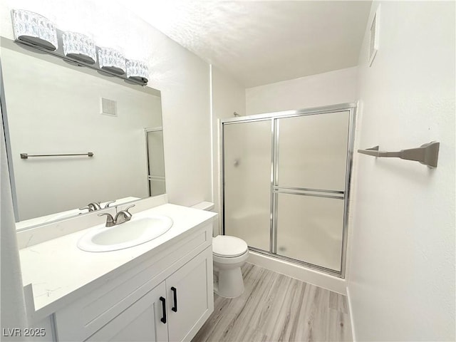 bathroom with visible vents, toilet, wood finished floors, a shower stall, and vanity