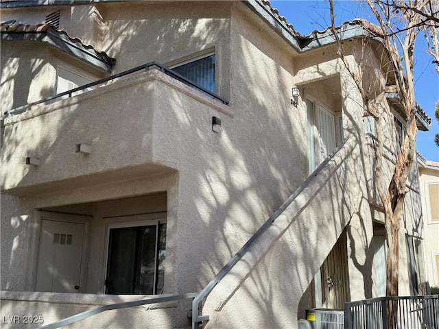 view of home's exterior featuring a tile roof, central AC unit, and stucco siding