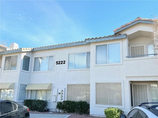 townhome / multi-family property featuring a tile roof and stucco siding