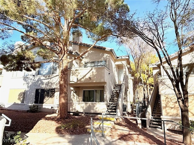 exterior space featuring stucco siding, a chimney, and stairs